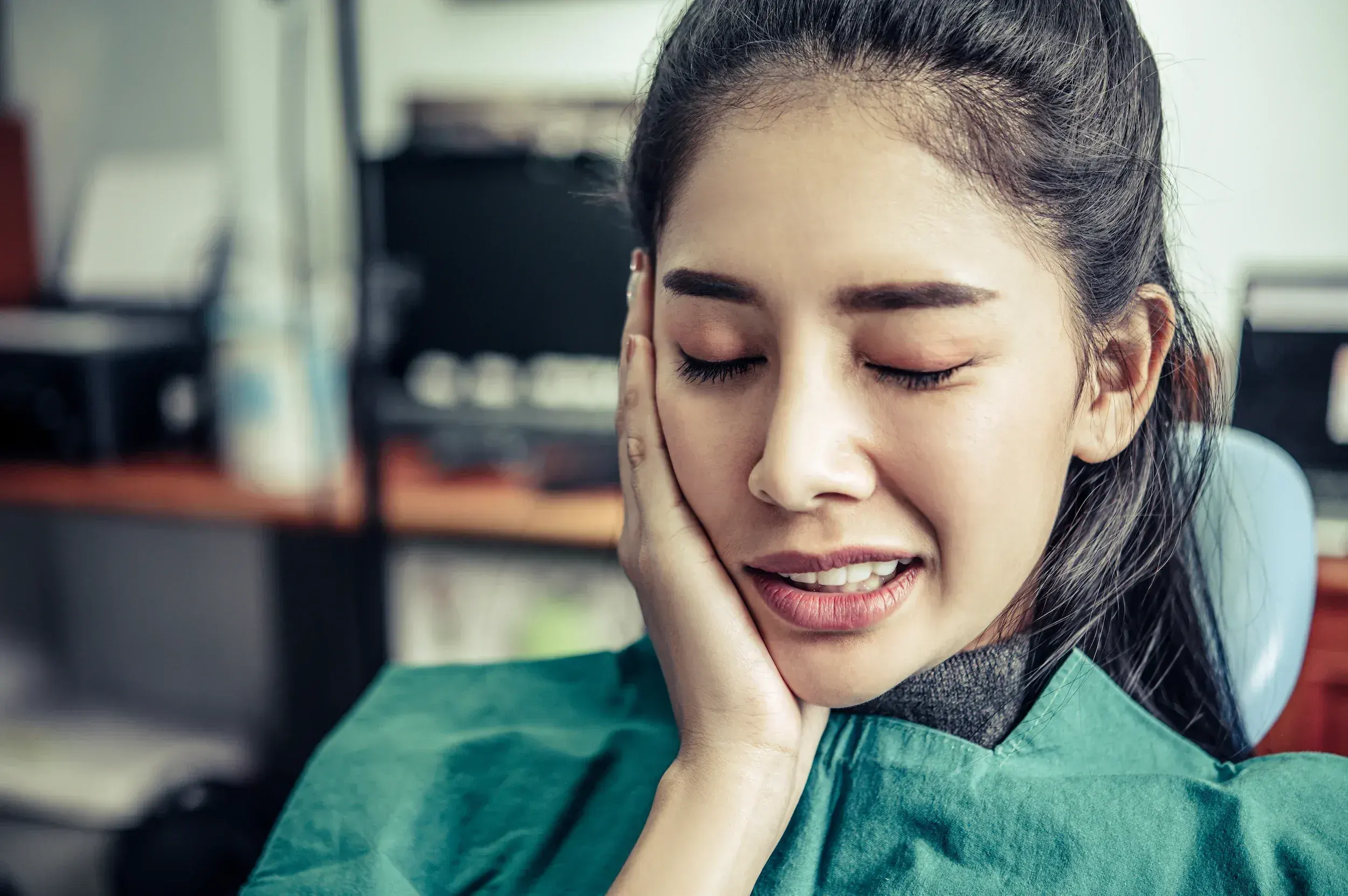 Woman holding her jaw from TMJ pain at Face and Body by Hartley Medispa Canton