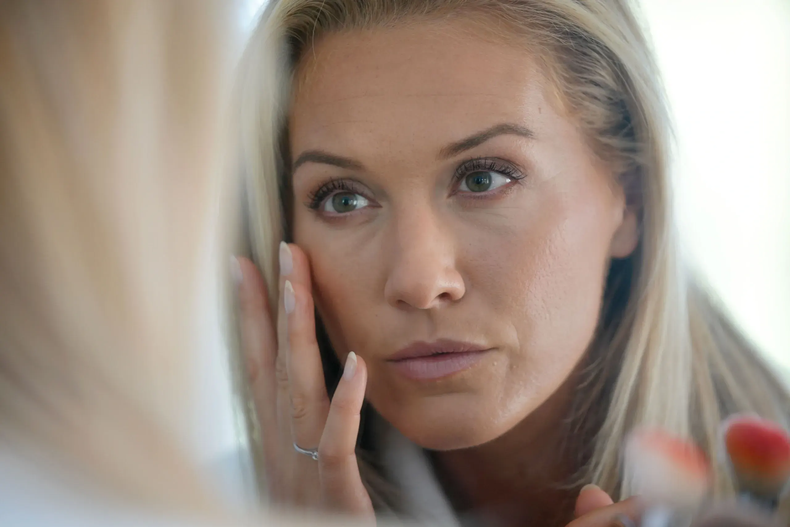 Woman evaluating her wrinkles in a mirror at Hartley Health and Wellness Canton